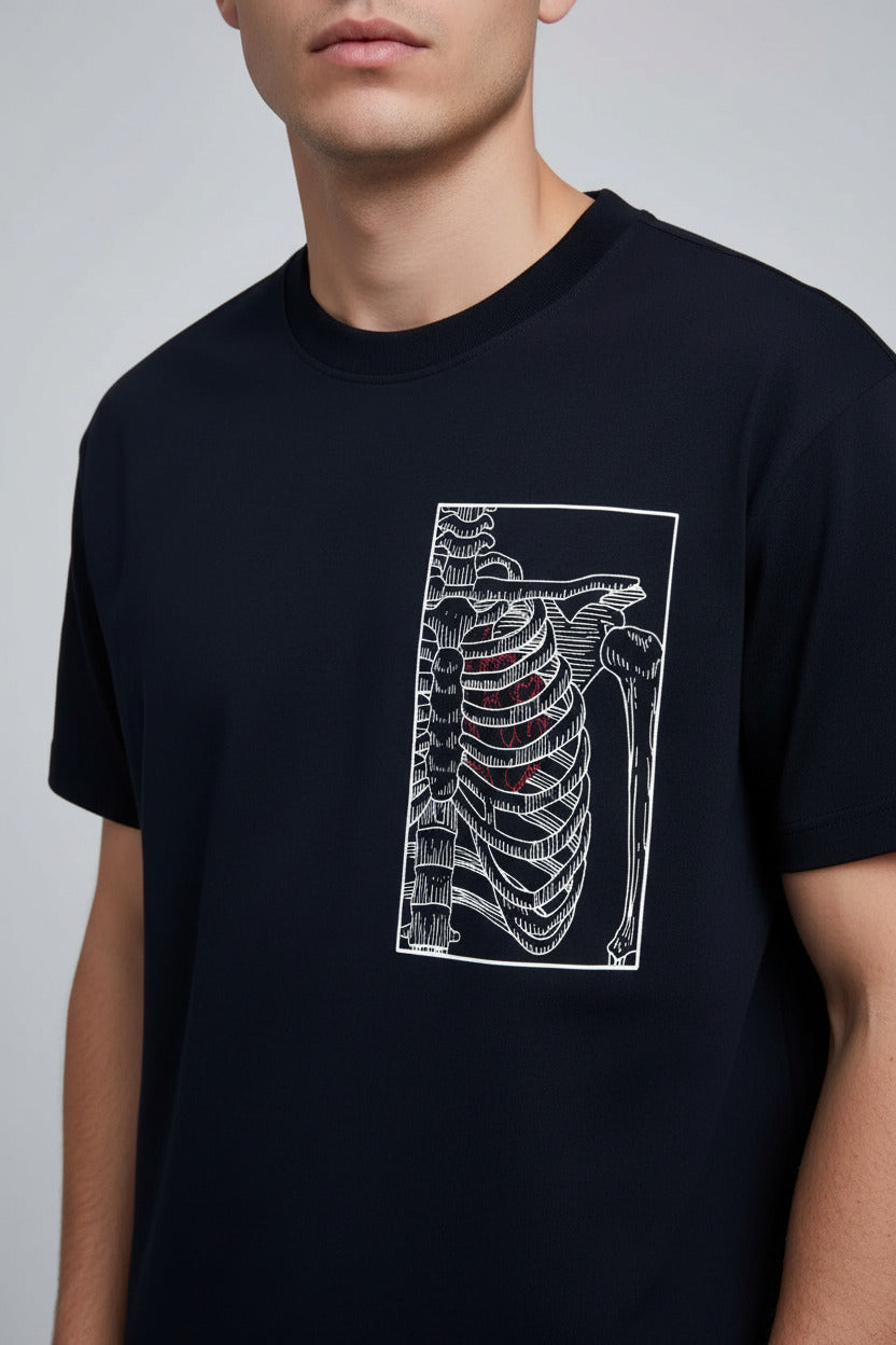 A navy blue short-sleeve t-shirt on a wooden hanger, featuring a white anatomical rib cage graphic on the chest. The hanger is held up by a hand in front of a modern, luxurious dark-toned dressing room background.