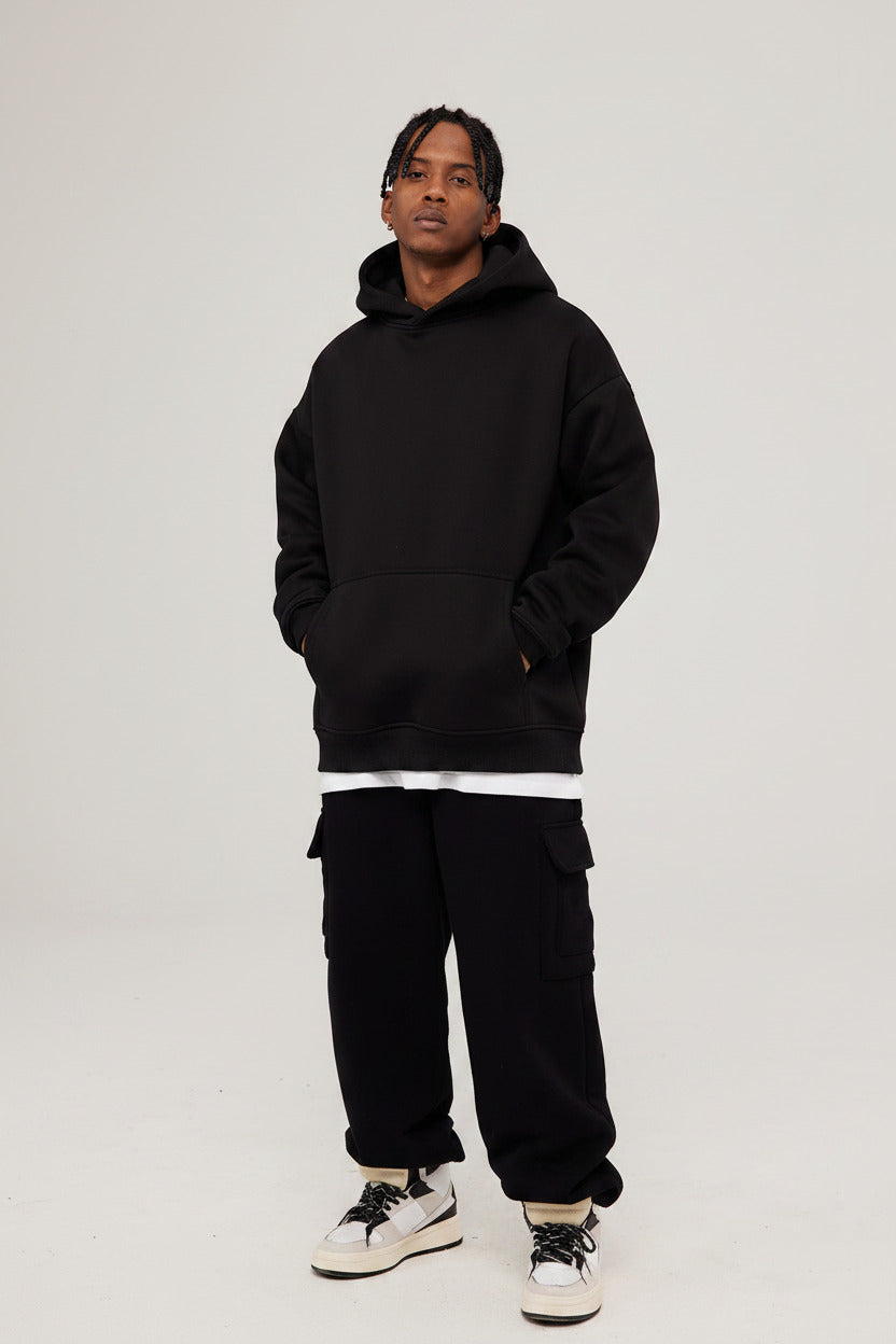 Person wearing a black hoodie and black pants on a white background