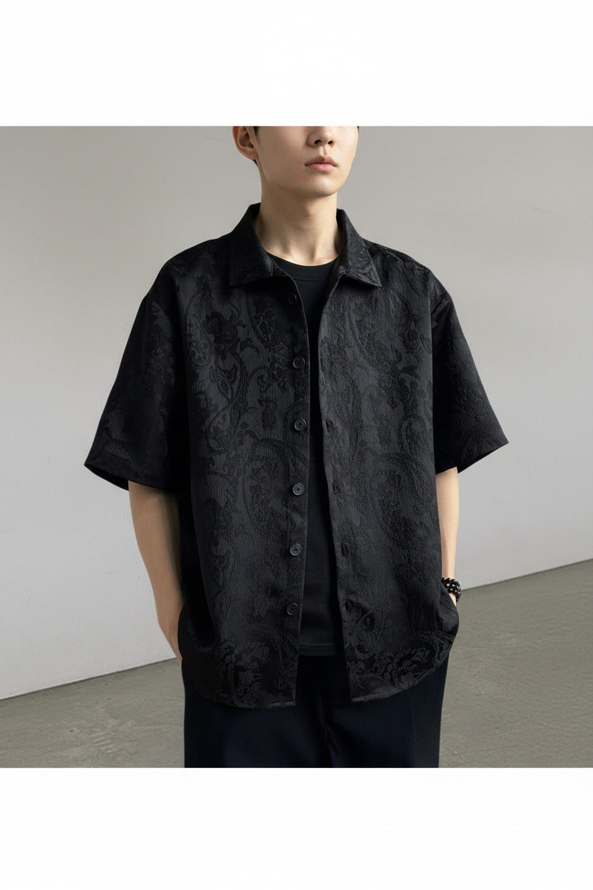 Person wearing a black textured shirt over a plain background