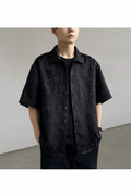 Person wearing a black textured shirt over a plain background