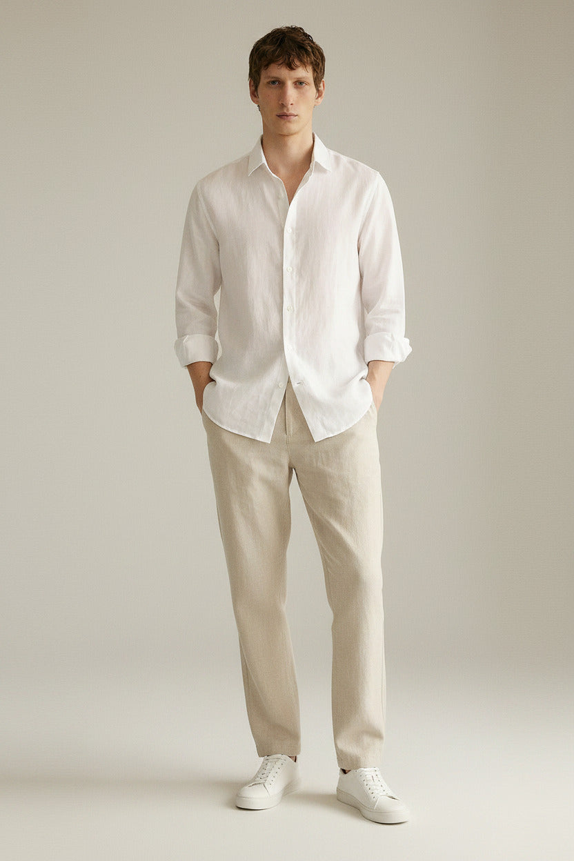 Man wearing a white linen shirt and beige pants against a neutral background