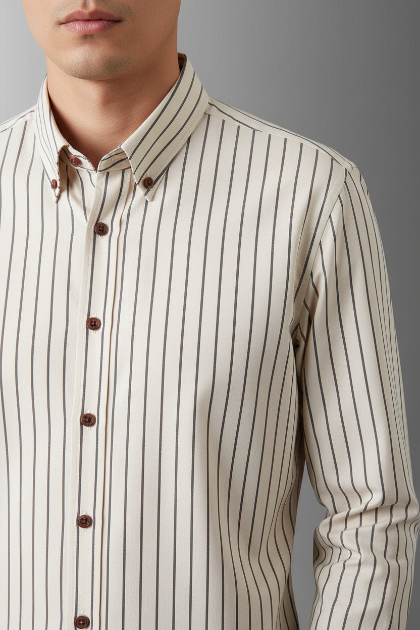 A long-sleeve button-up shirt with vertical thin stripes in brown and beige on an off-white base, displayed on a black hanger against a gray gradient background.