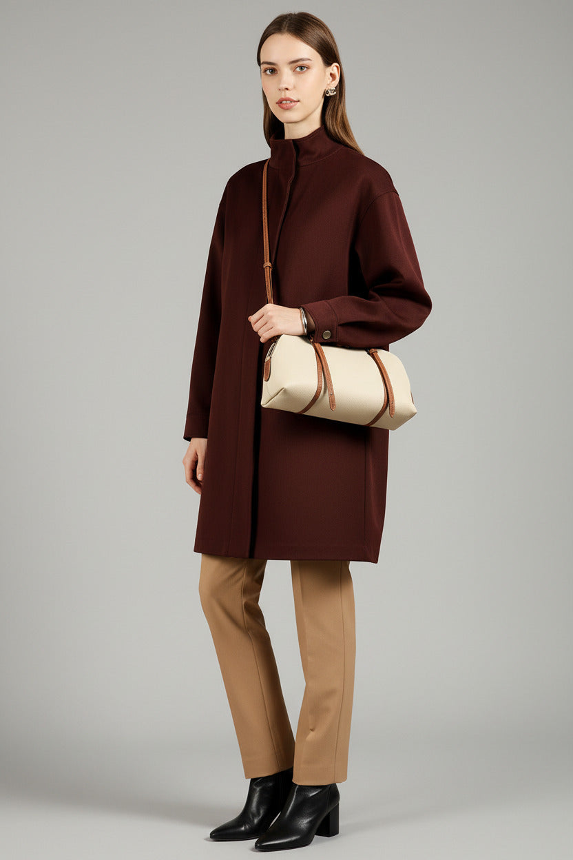 Woman holding a beige handbag with brown straps against a floral wallpaper background