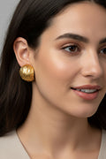 Gold earrings on a wooden stand with a marble background