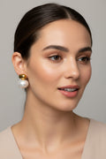 Pearl earrings with gold tops on a textured beige surface