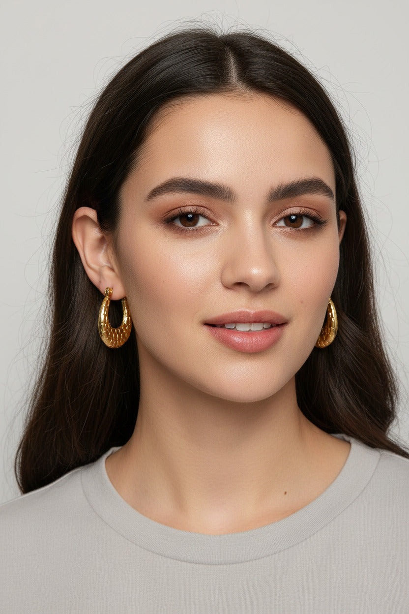 Gold-plated stainless steel crescent hoop earrings with a textured crocodile skin pattern, shown with dimension markings of 19mm width and 25mm height, and text indicating 18k gold plating and 9.49g weight.