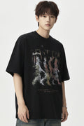 A young man wearing a black graphic t-shirt with a colorful abstract print, blue jeans, and silver headphones, posing against a light gray studio background.