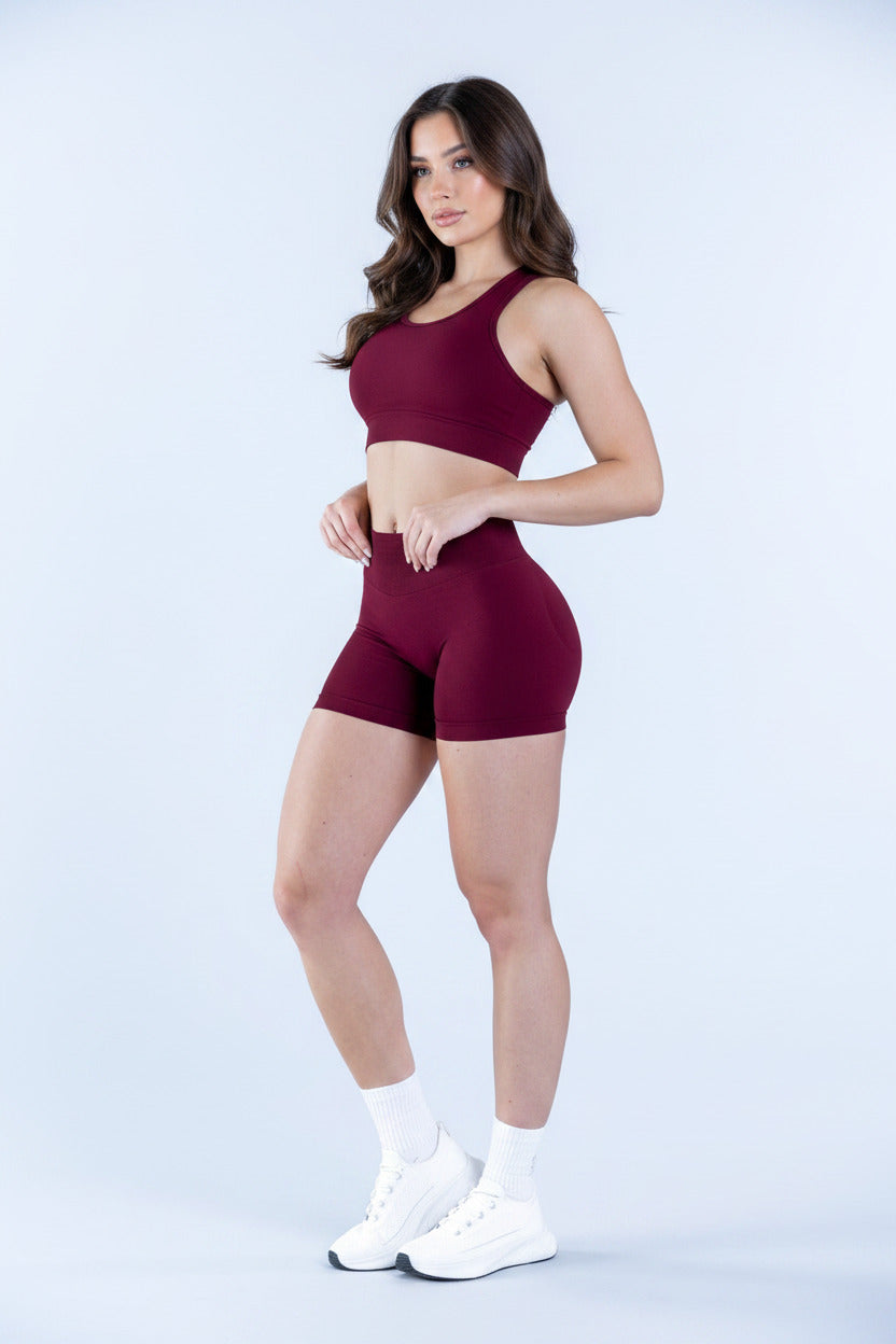 Person wearing maroon high-waisted shorts and white sneakers on a light blue background