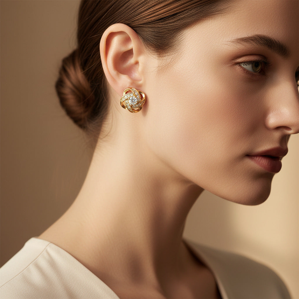 Gold earrings with diamond accents on a beige fabric background