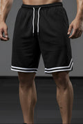 Person wearing black shorts with white trim on a gray background