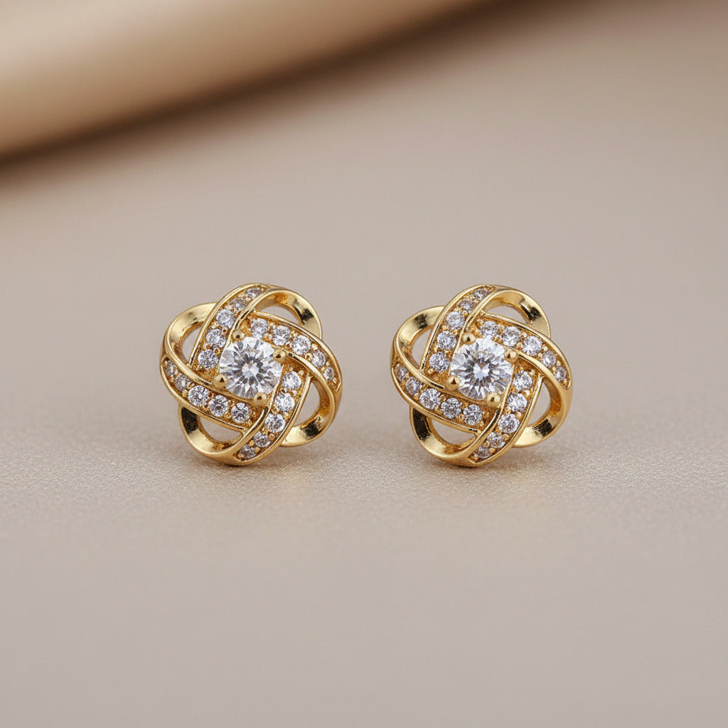 Gold earrings with diamond accents on a dark blue stand with beige fabric background