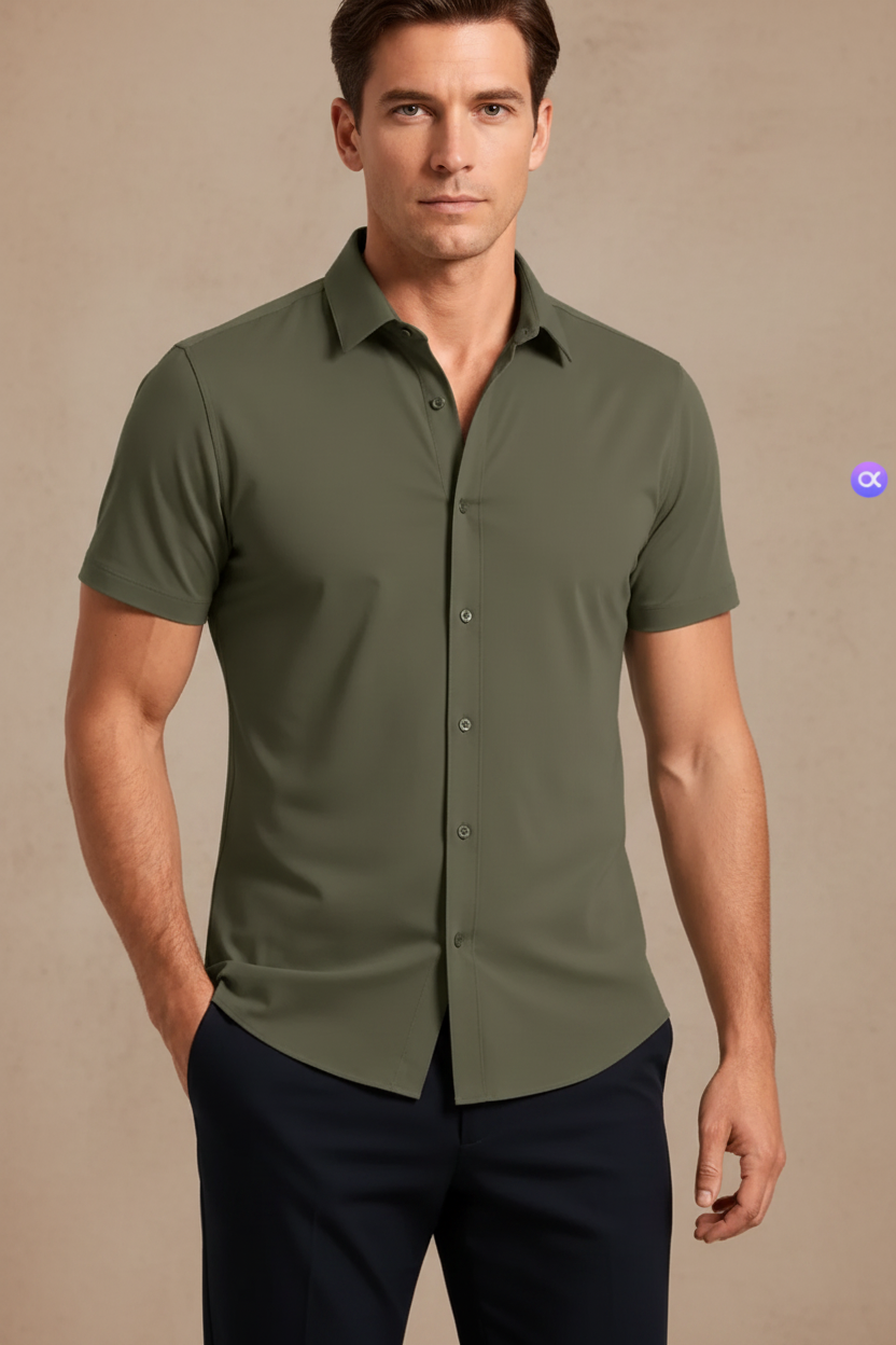 A man wearing an olive green short-sleeve button-up shirt, pulling the fabric outward on the right side to demonstrate its stretch, against a light gray studio background.