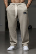 Beige waffle-textured pants with a brand logo worn by a person on a white background