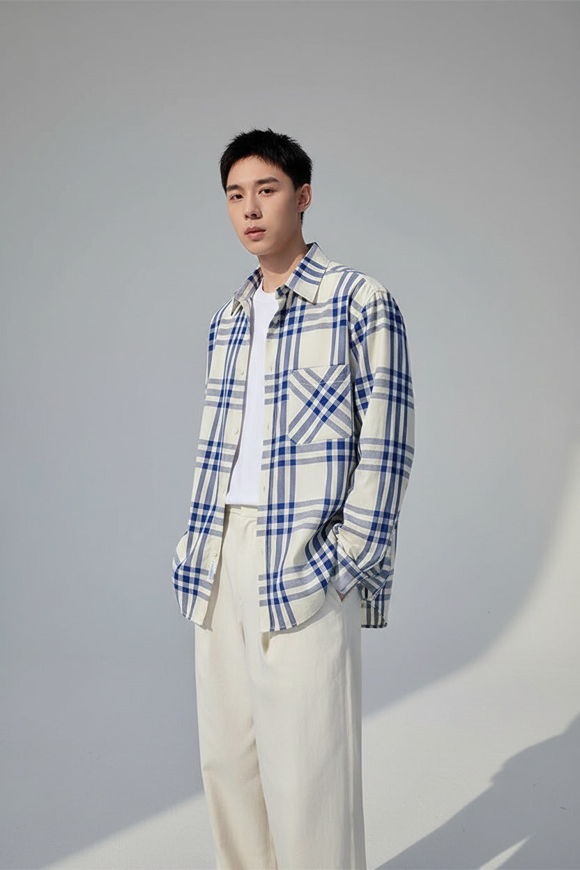 Person sitting by a lake wearing a blue and white checkered shirt with a blurred background