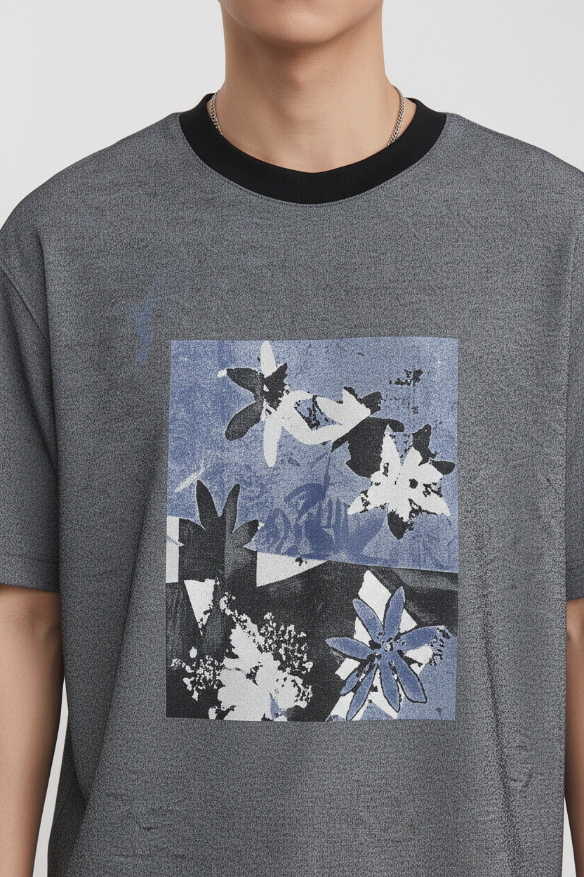 Person wearing a gray t-shirt with a floral design on a plain background