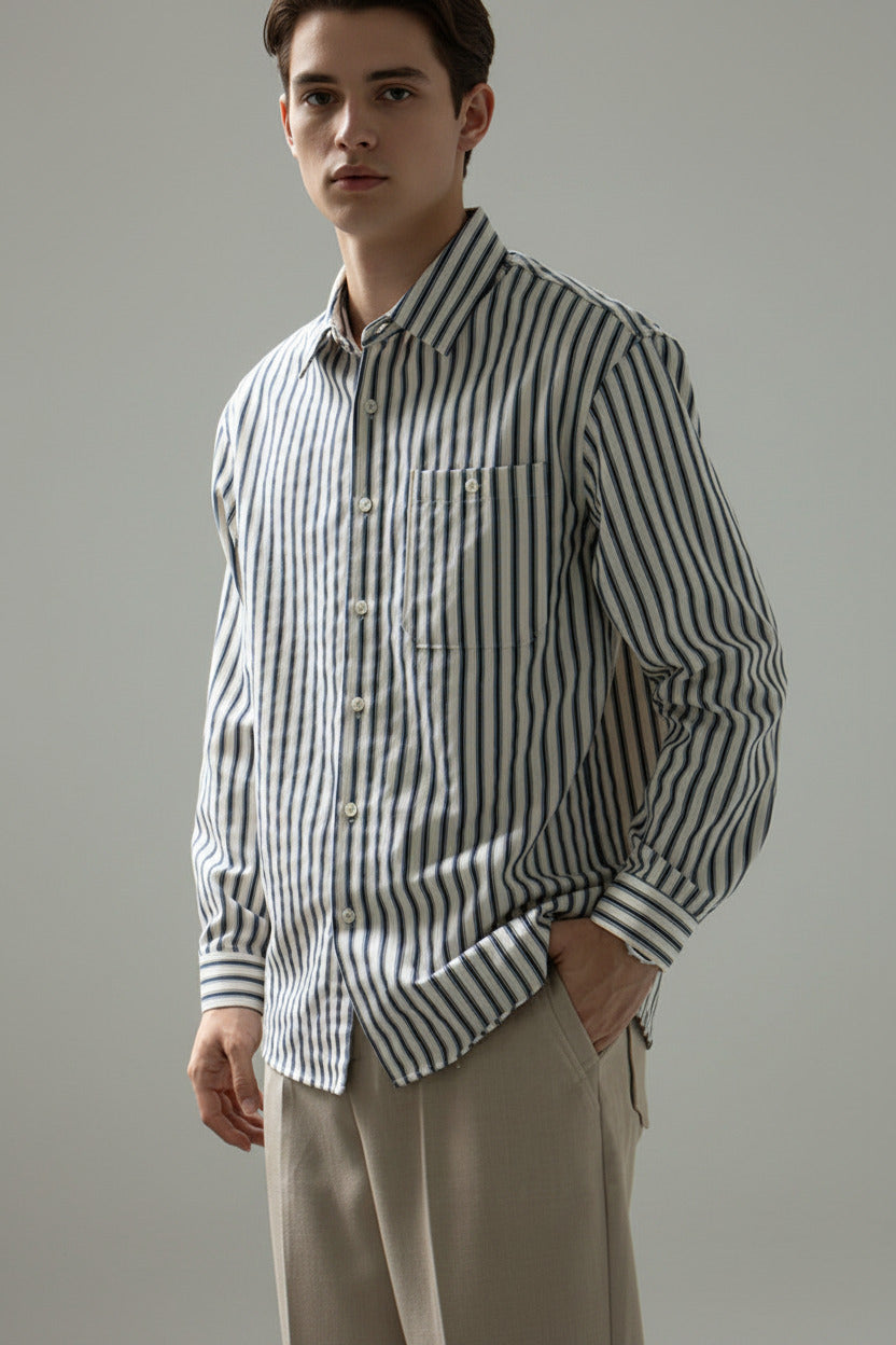 Person wearing a black and white striped shirt with a neutral background